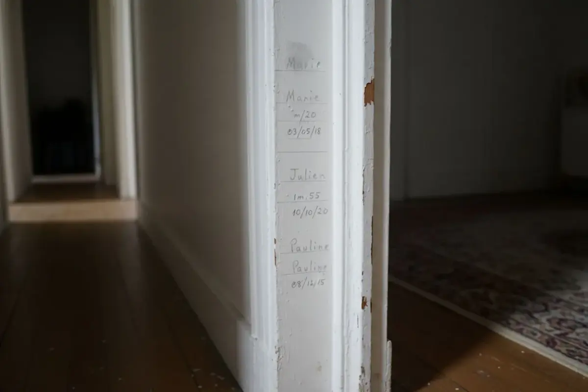 Chambranle de porte blanc marqué au crayon des tailles et des dates des enfants